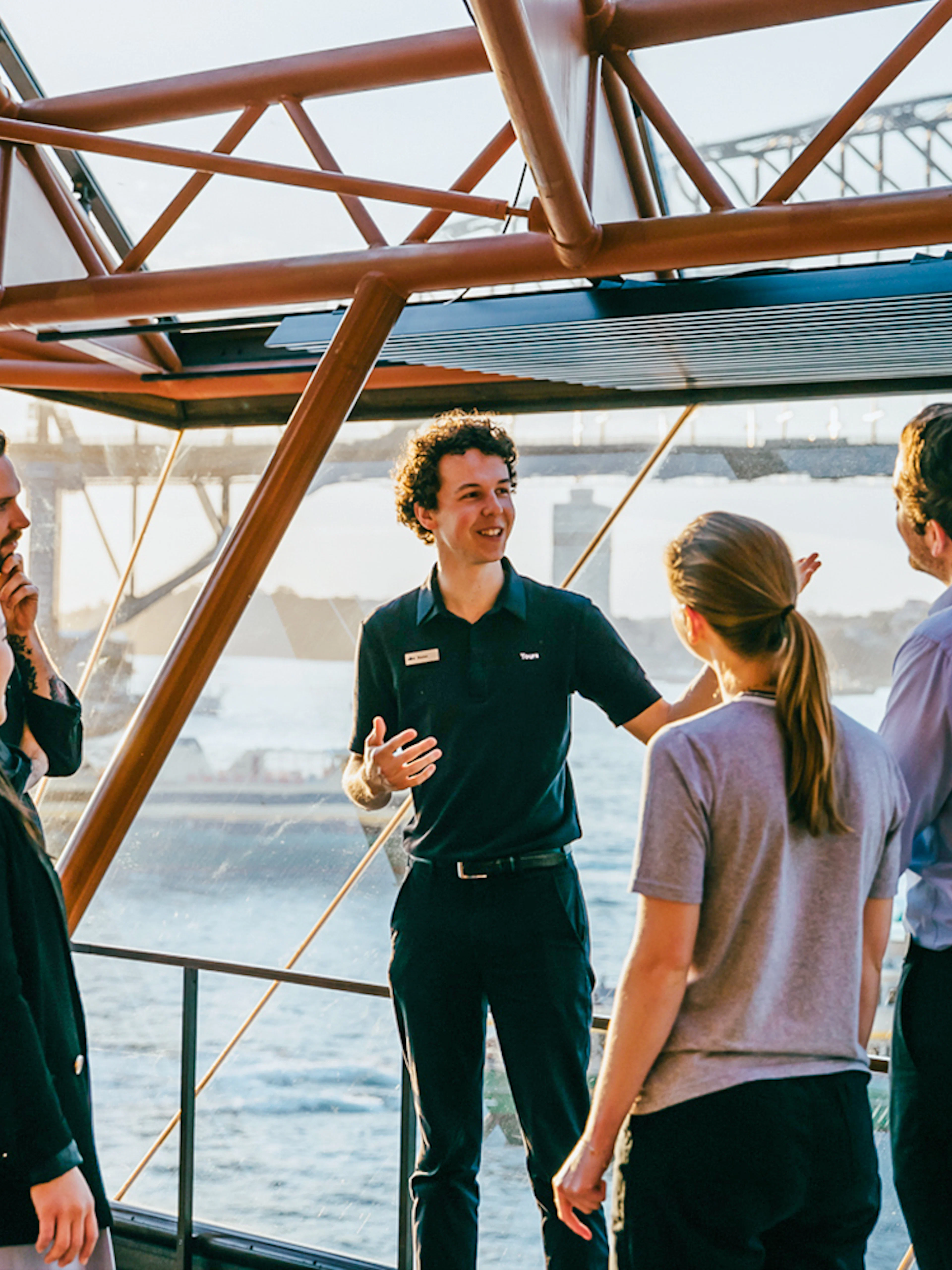 Tour guide leading a group at Sydney Opera House with Harbour Bridge view.