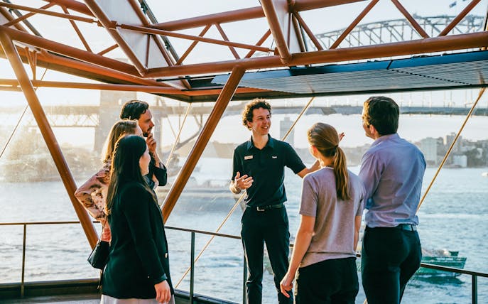 Tour guide leading a group at Sydney Opera House with Harbour Bridge view.