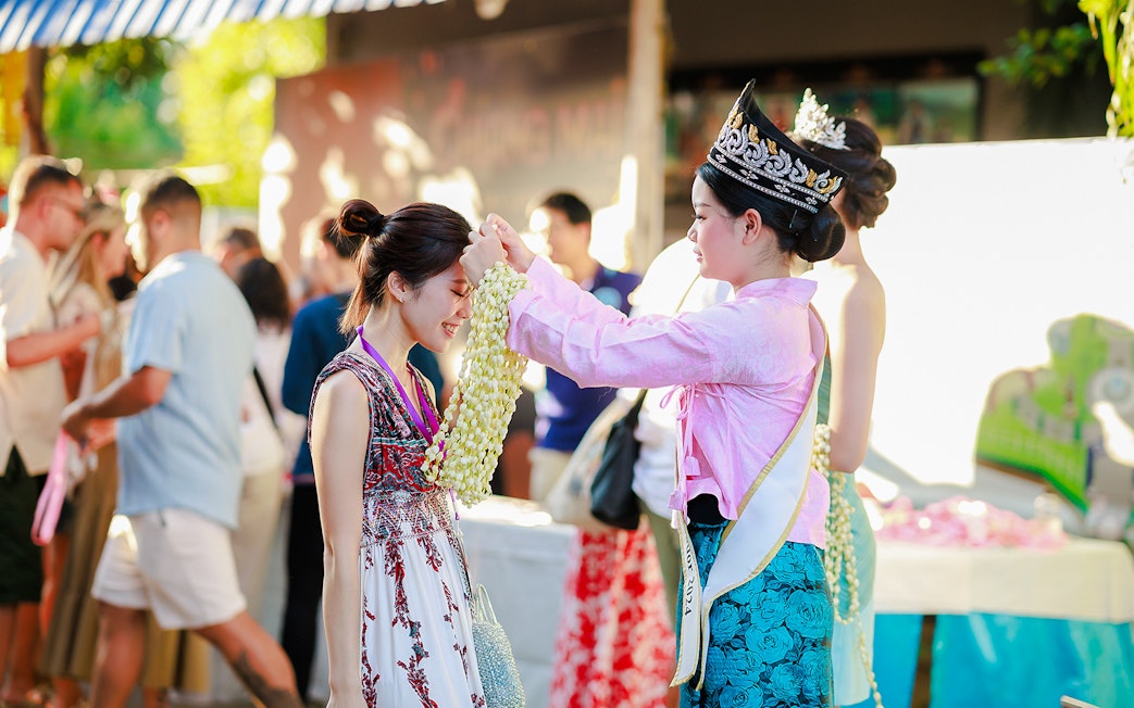 Ambassador in Thai attire presents jasmine garland to visitor at Sky Lanterns Festival.