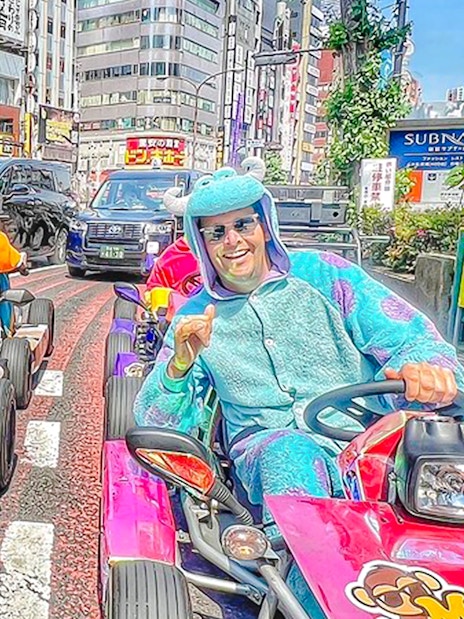 Couple in costumes driving go-karts on Shibuya streets, Tokyo.