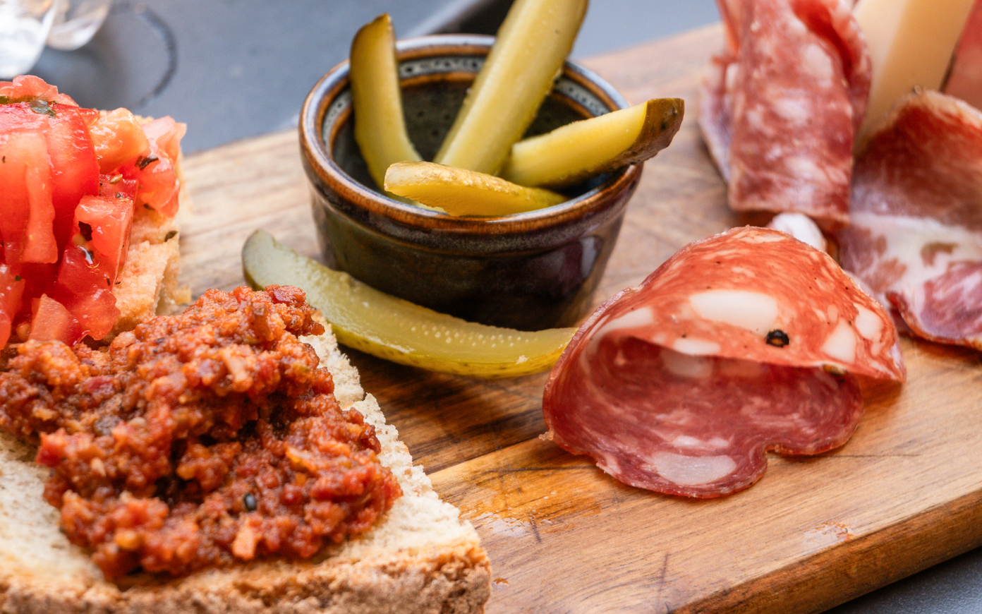Pisan specialties with bruschetta, salami, and pickles on a wooden board during Pisa guided tour.