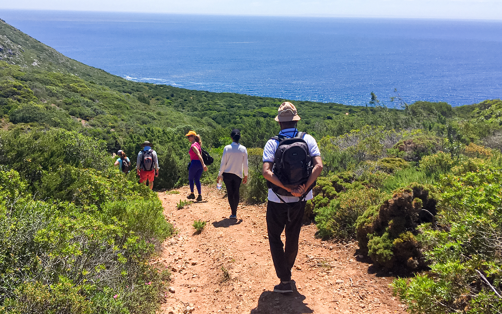 Hikers walking along a trail with ocean view at Arrábida Natural Park.