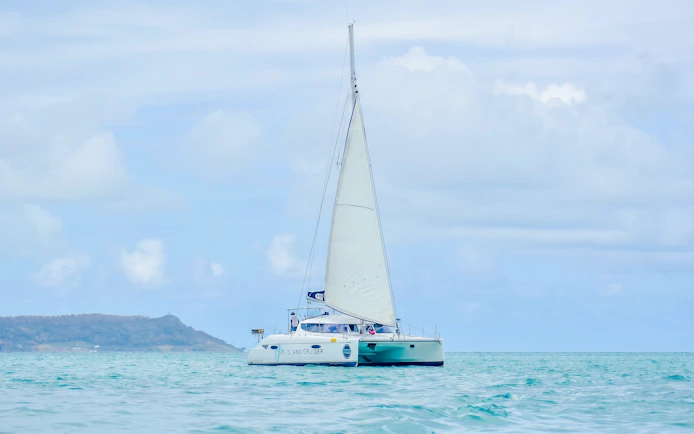 Catamaran sailing towards Ile aux Cerf for parasailing and tube riding adventure.