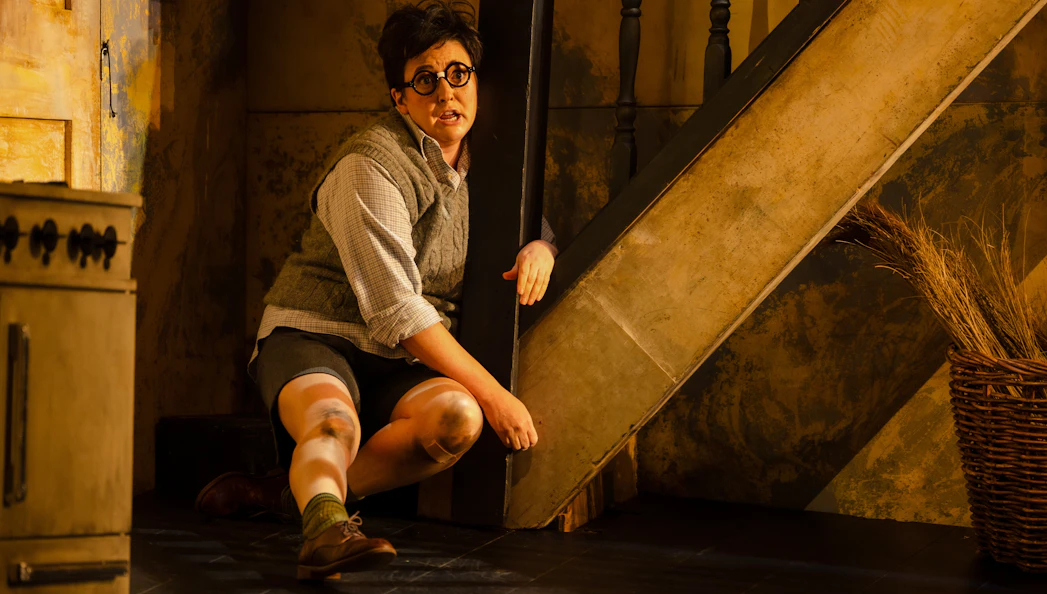 Actor crouching under stairs during Hansel and Gretel stage performance.