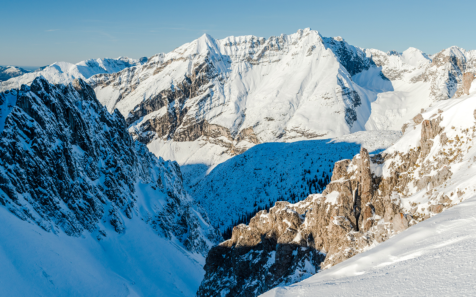 Snow-covered Alps in Innsbruck, Austria, showcasing rugged mountain peaks and a clear blue sky.