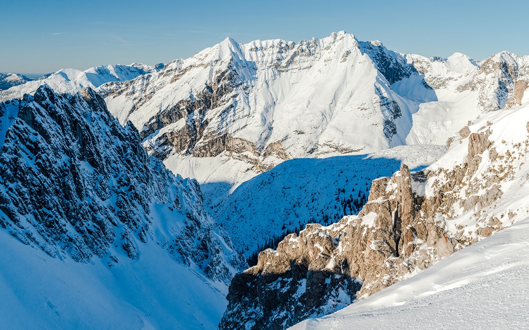 Snow-covered Alps in Innsbruck, Austria, showcasing rugged mountain peaks and a clear blue sky.
