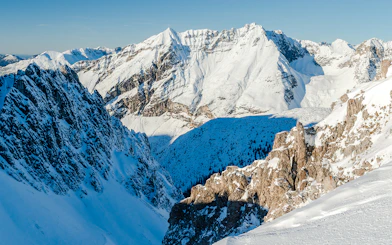Snow-covered Alps in Innsbruck, Austria, showcasing rugged mountain peaks and a clear blue sky.