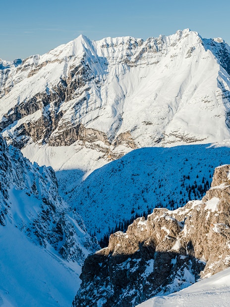 Snow-covered Alps in Innsbruck, Austria, showcasing rugged mountain peaks and a clear blue sky.