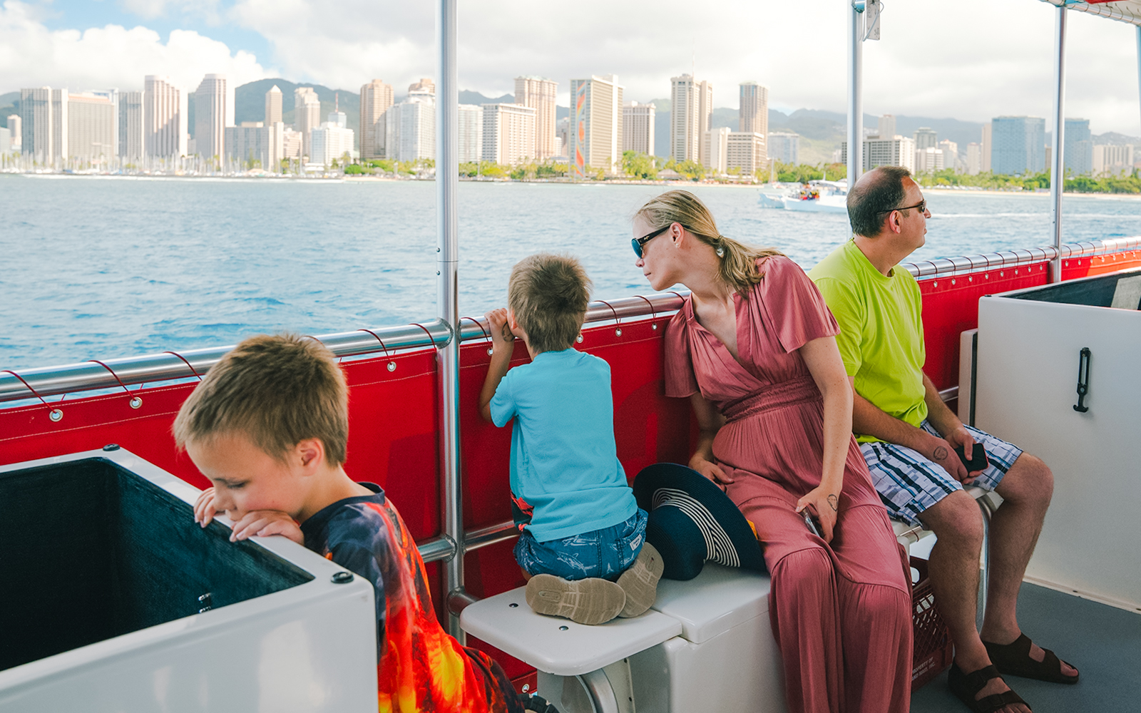 Guests on a Hawaii glass-bottom boat tour with Honolulu skyline in the background.