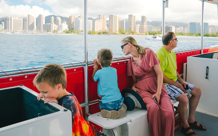 Guests on a Hawaii glass-bottom boat tour with Honolulu skyline in the background.