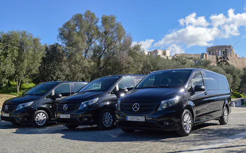 Minivans parked near the Acropolis in Athens for airport transfer service.