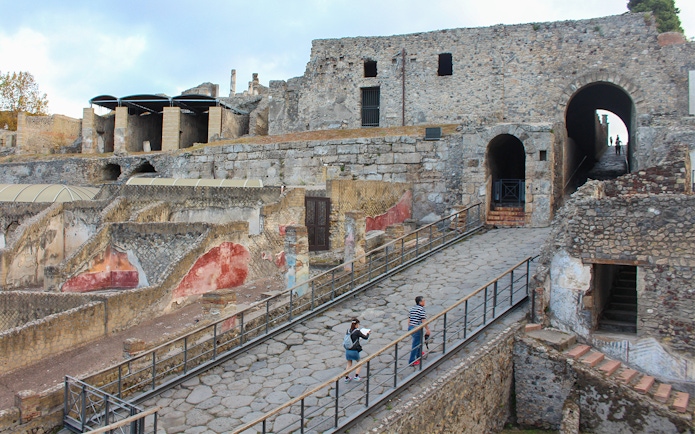 Visitors ascending a stone path at Pompeii ruins, Italy.