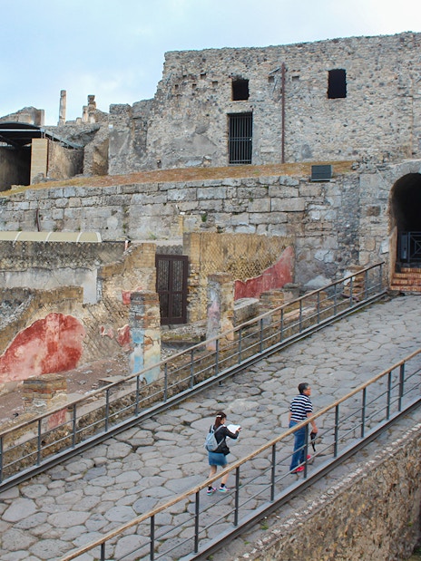 Visitors ascending a stone path at Pompeii ruins, Italy.