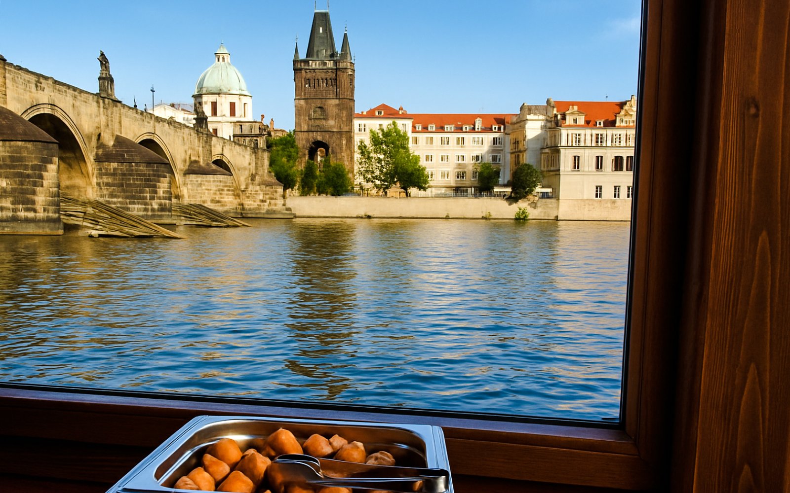 Buffet lunch with view of Charles Bridge during Prague river cruise.