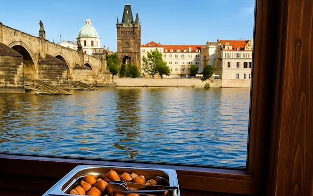 Buffet lunch with view of Charles Bridge during Prague river cruise.