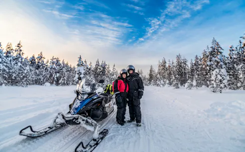 Snowmobile ride through snowy forest at Santa Village, Rovaniemi.