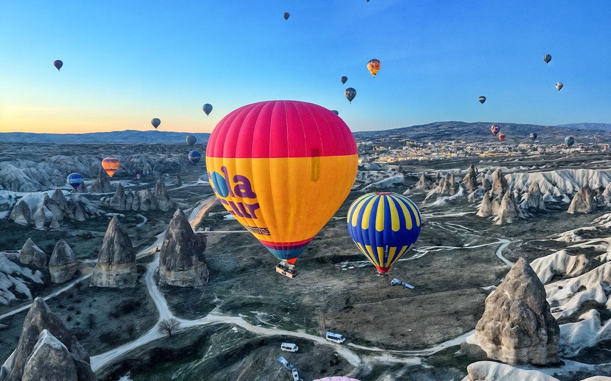 Hot air balloons floating over Gerome Valley, Cappadocia's unique rock formations.