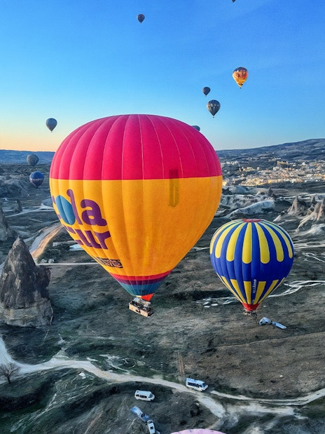 Hot air balloons floating over Gerome Valley, Cappadocia's unique rock formations.