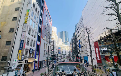 Tokyo street view from Sky Hop Bus on a sunny day, showcasing modern buildings and bustling sidewalks.
