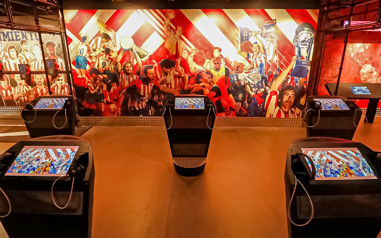 Interactive exhibit at Atletico de Madrid Stadium Museum with vibrant mural and digital displays.