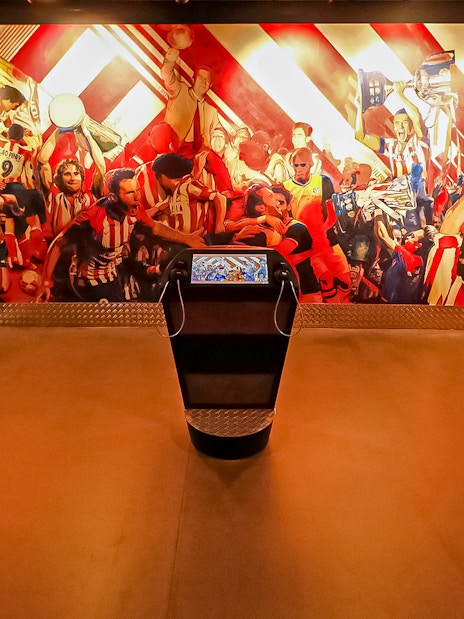 Interactive exhibit at Atletico de Madrid Stadium Museum with vibrant mural and digital displays.
