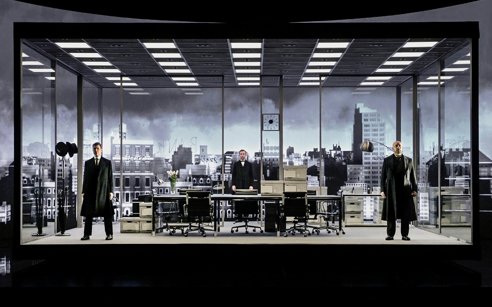 Stage set of "The Lehman Trilogy" with three actors in an office scene.
