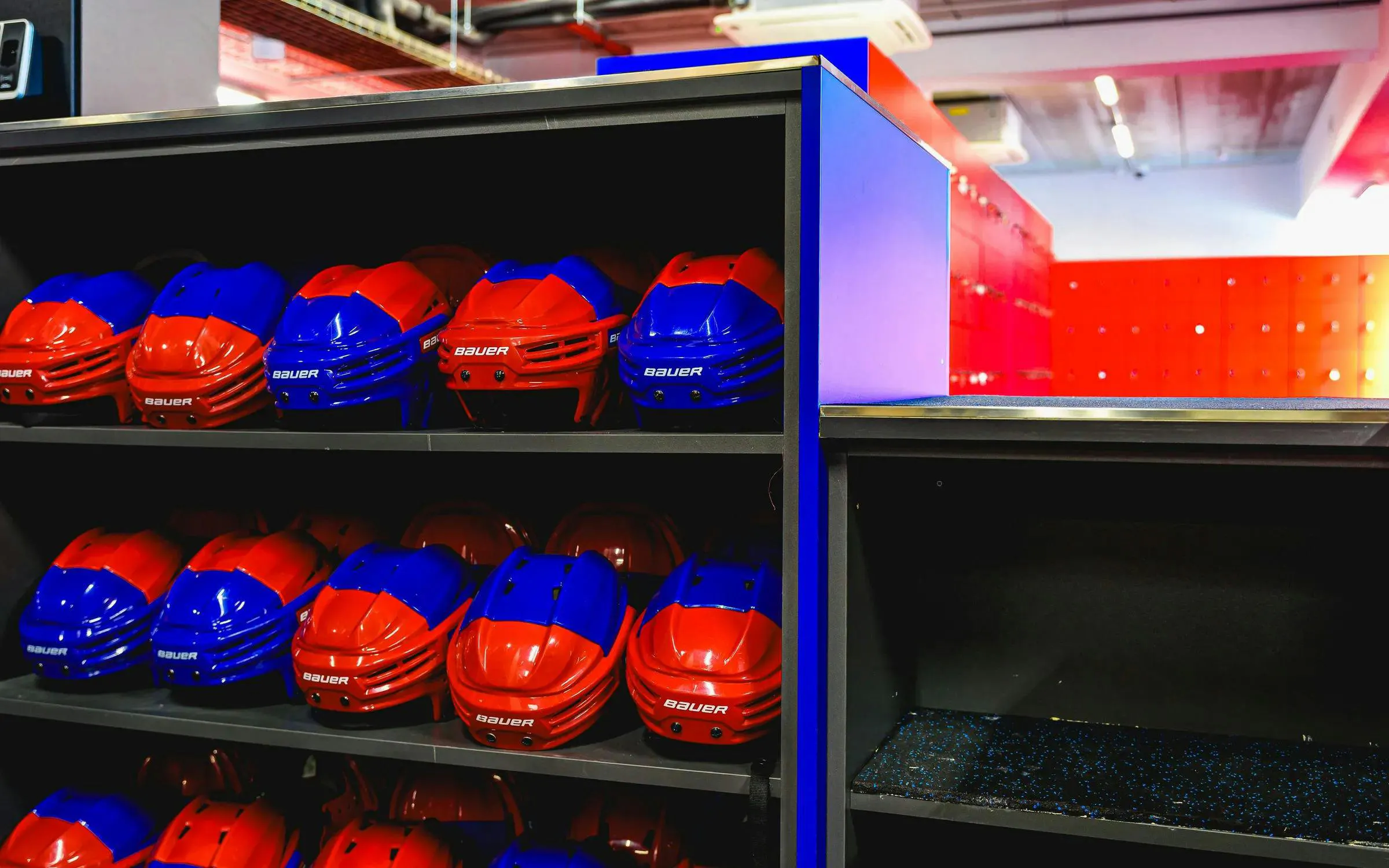 Red and blue helmets on shelves in FC Barcelona Ice Rink equipment room.