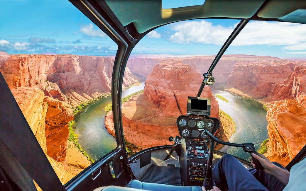 Helicopter cockpit view of the Grand Canyon with winding river below.