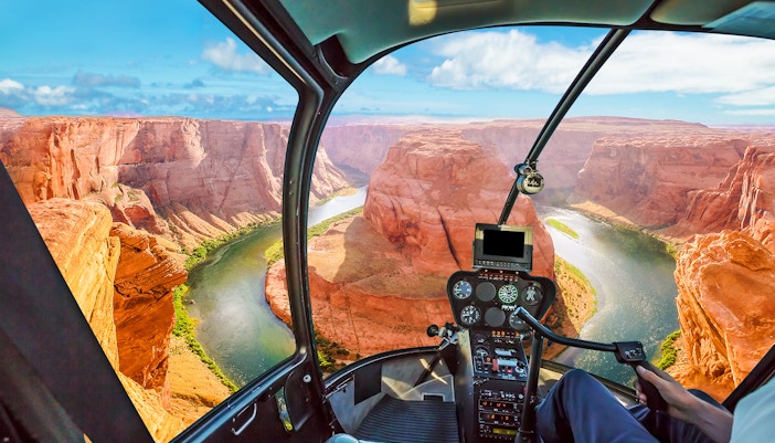 Helicopter cockpit view of the Grand Canyon with winding river below.