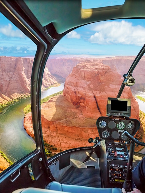 Helicopter cockpit view of the Grand Canyon with winding river below.