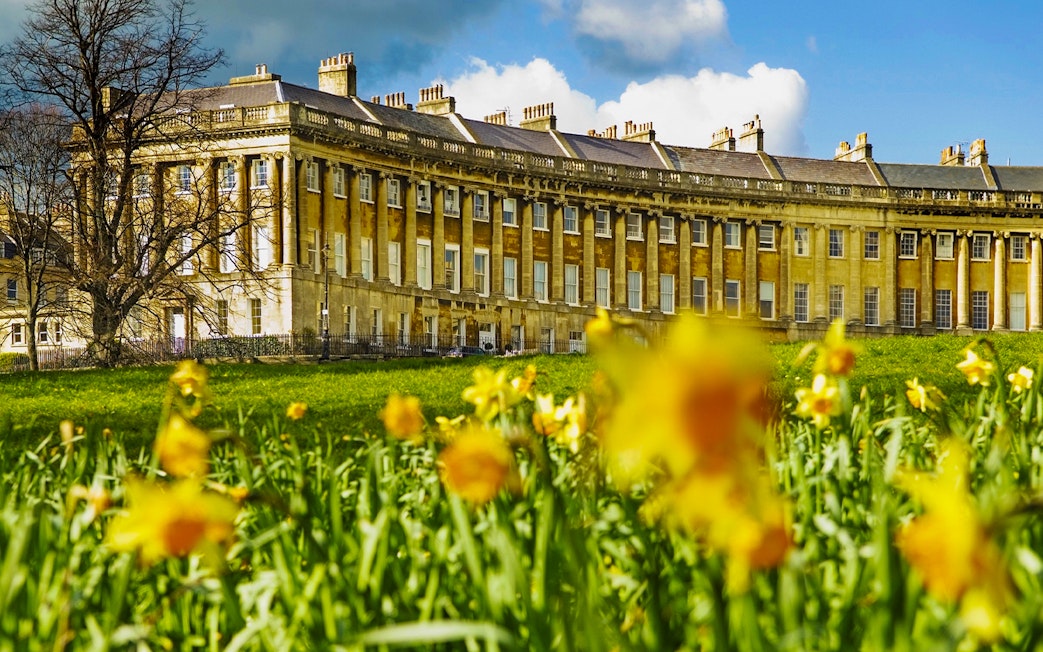 Royal Crescent in Bath, UK with blooming daffodils in the foreground.
