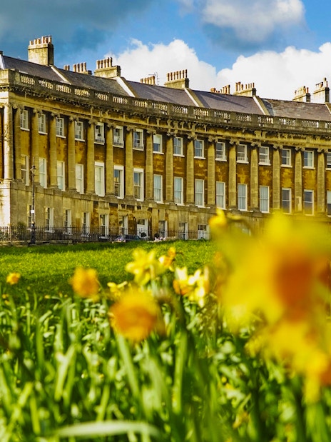 Royal Crescent in Bath, UK with blooming daffodils in the foreground.