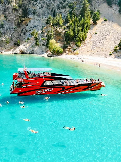 Tourists swimming near a red boat in St George's Bay, Rhodes.