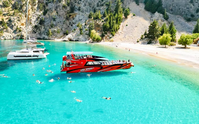 Tourists swimming near a red boat in St George's Bay, Rhodes.