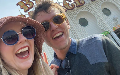 Couple smiling in front of Brighton Palace Pier entrance during self-guided city exploration game.
