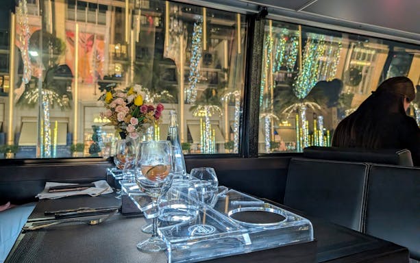 Dining table setup inside Bustronome Restaurant, Dubai with city lights visible through the window.