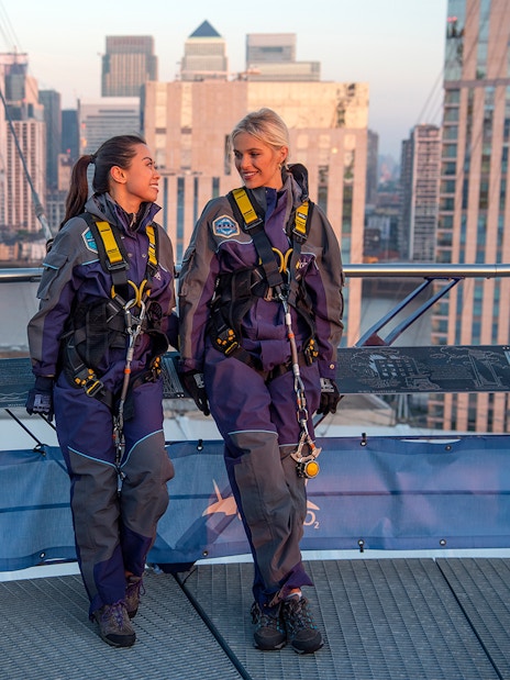 Guests in climbing gear at the O2 Arena rooftop during sunset in London.