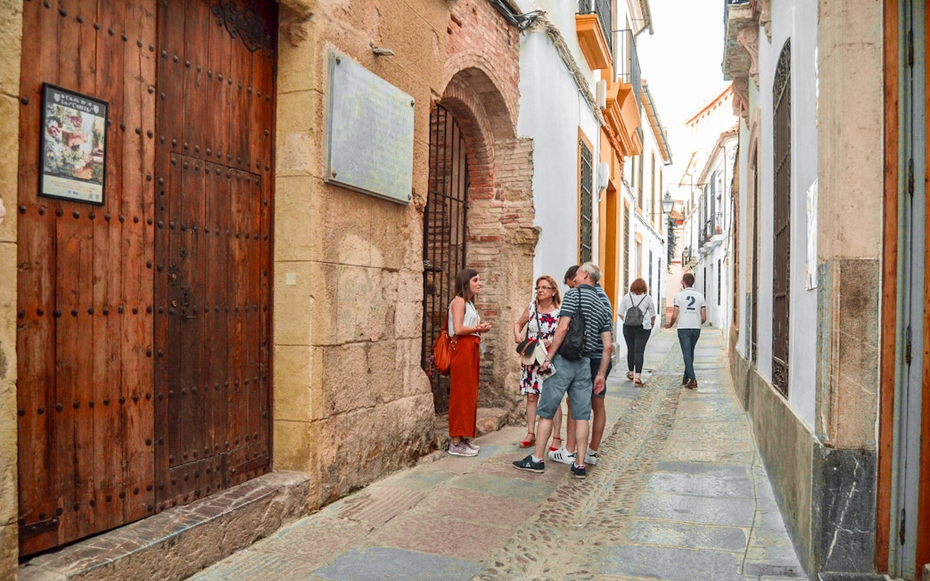 Tourists exploring a narrow street in Cordoba's Jewish Quarter.