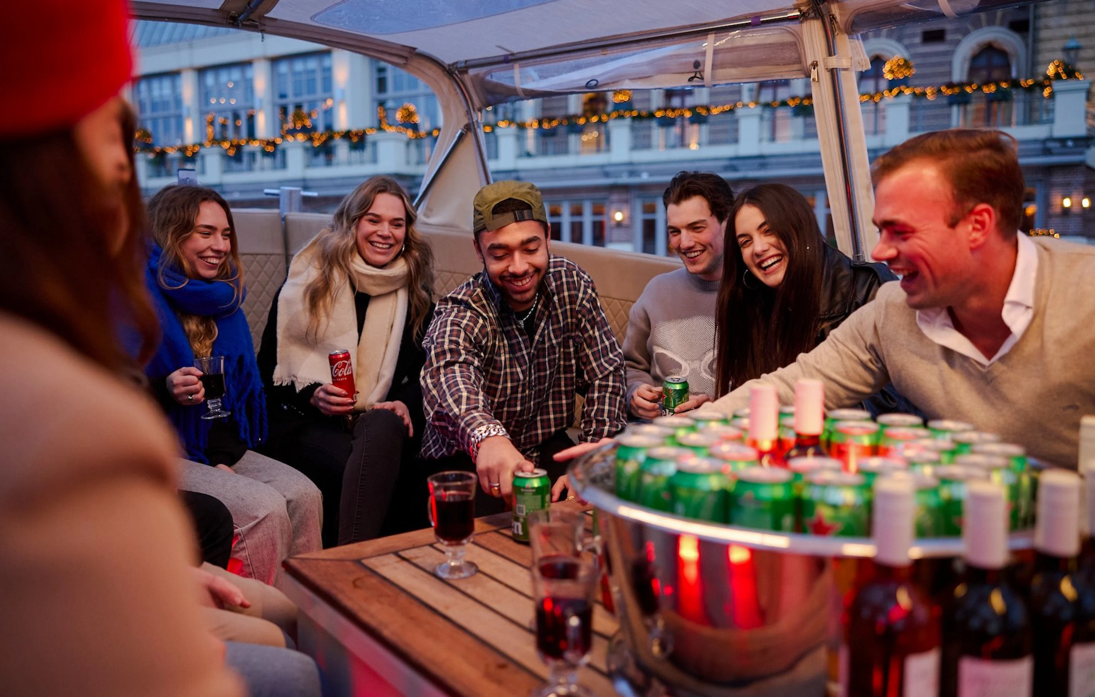 Guests enjoying drinks on a covered canal cruise in Amsterdam.