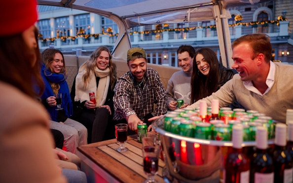 Guests enjoying drinks on a covered canal cruise in Amsterdam.