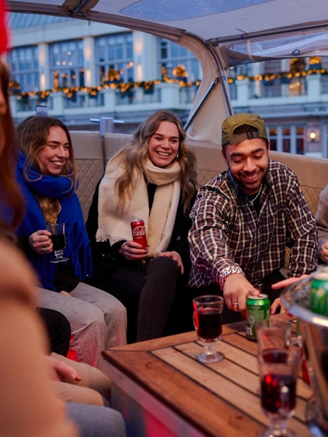 Guests enjoying drinks on a covered canal cruise in Amsterdam.