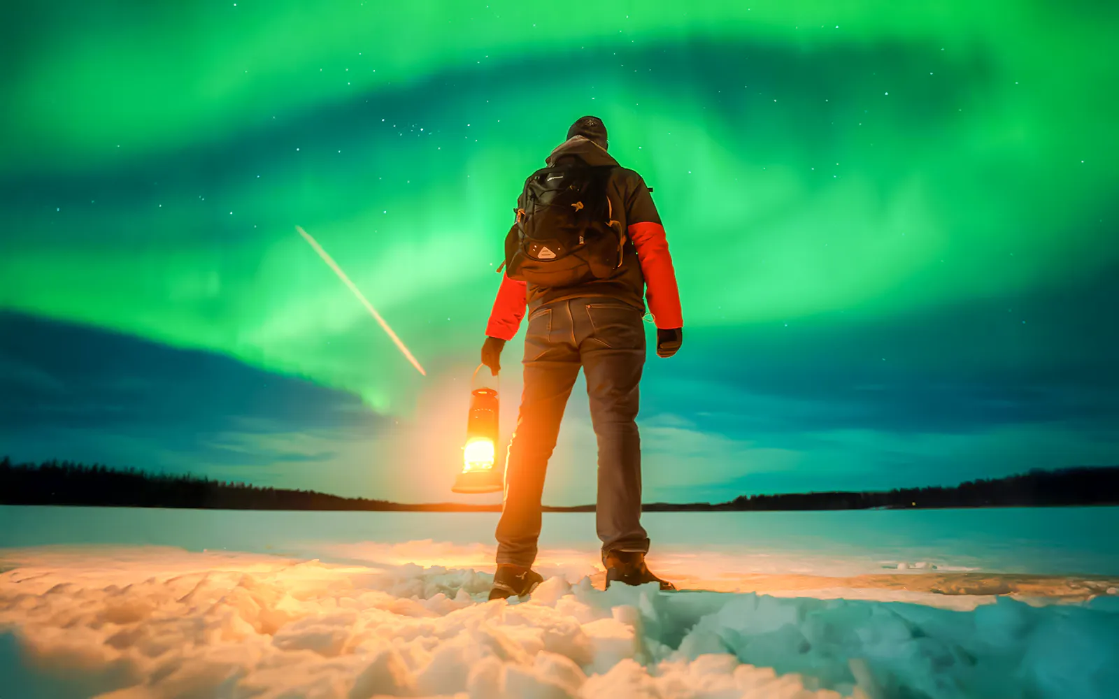 Person holding lantern under Northern Lights in Rovaniemi.