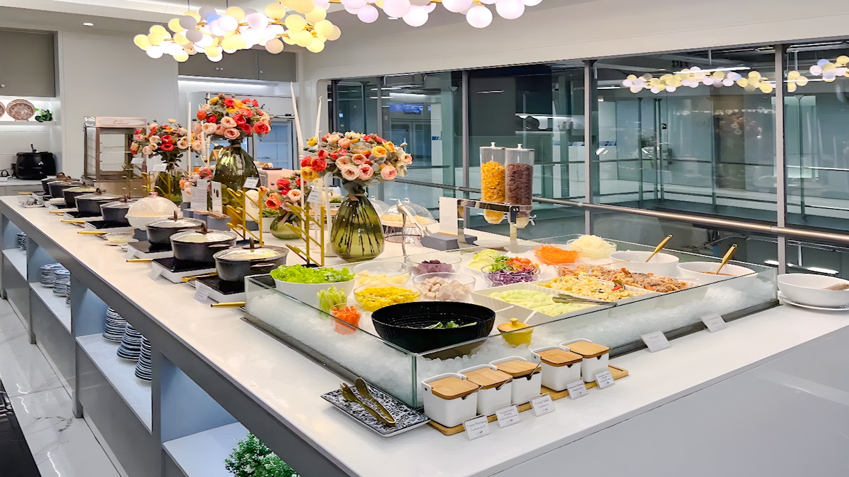 Buffet spread at Coral Finest Business Class Lounge, Bangkok airport, featuring salads and hot dishes.
