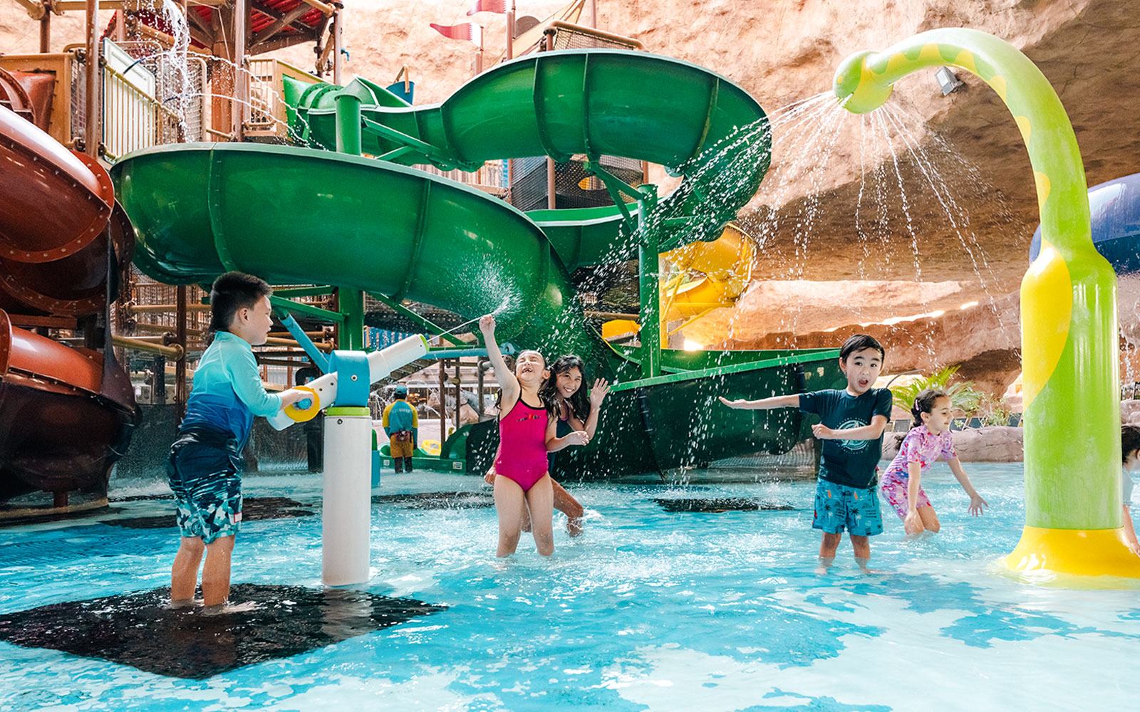 Children playing near a water slide in an indoor water park in Doha.