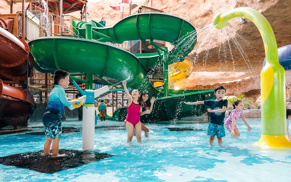 Children playing near a water slide in an indoor water park in Doha.