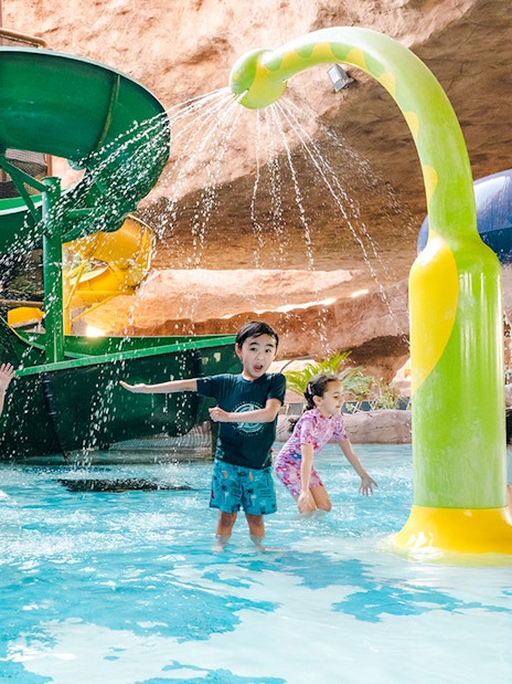 Children playing near a water slide in an indoor water park in Doha.