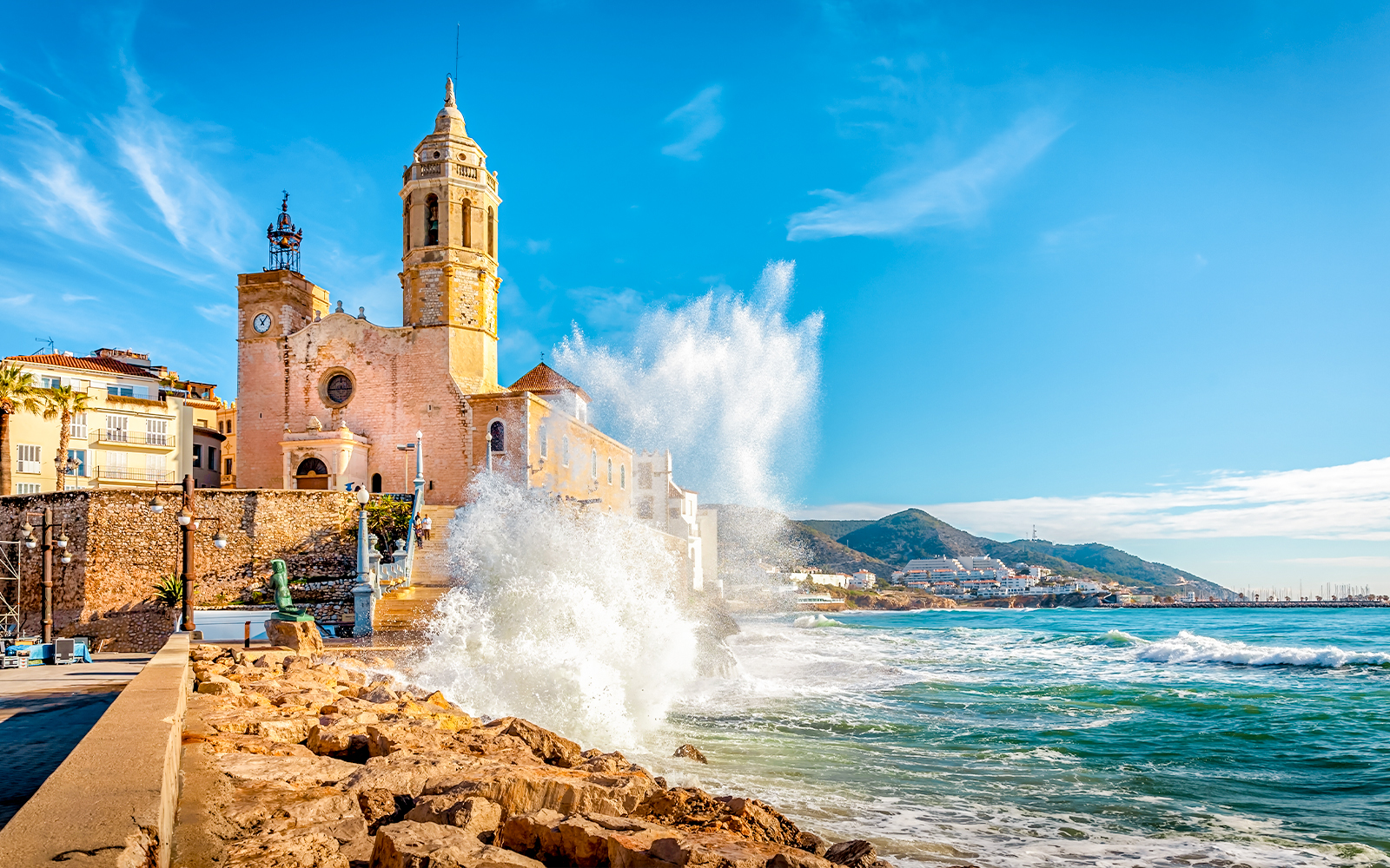 Church of Sant Bartomeu and Santa Tecla with waves crashing in Sitges, near Barcelona.