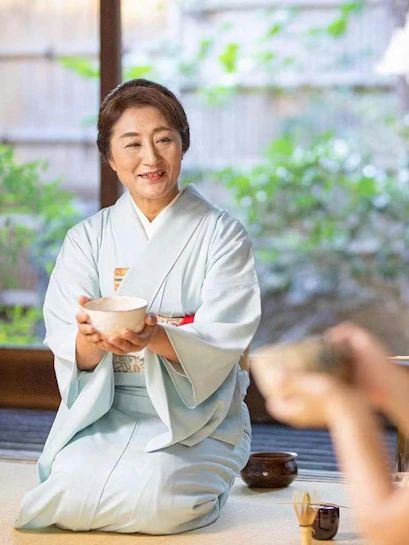 Tea ceremony host in traditional kimono serving tea in Kyoto.
