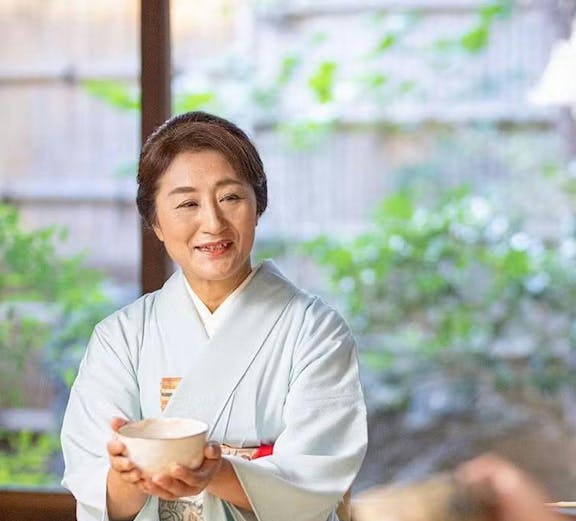 Tea ceremony host in traditional kimono serving tea in Kyoto.