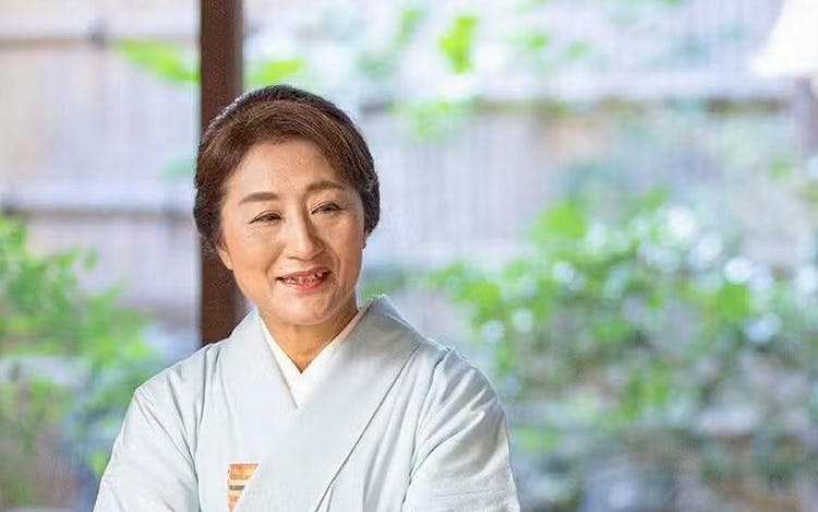 Tea ceremony host in traditional kimono serving tea in Kyoto.